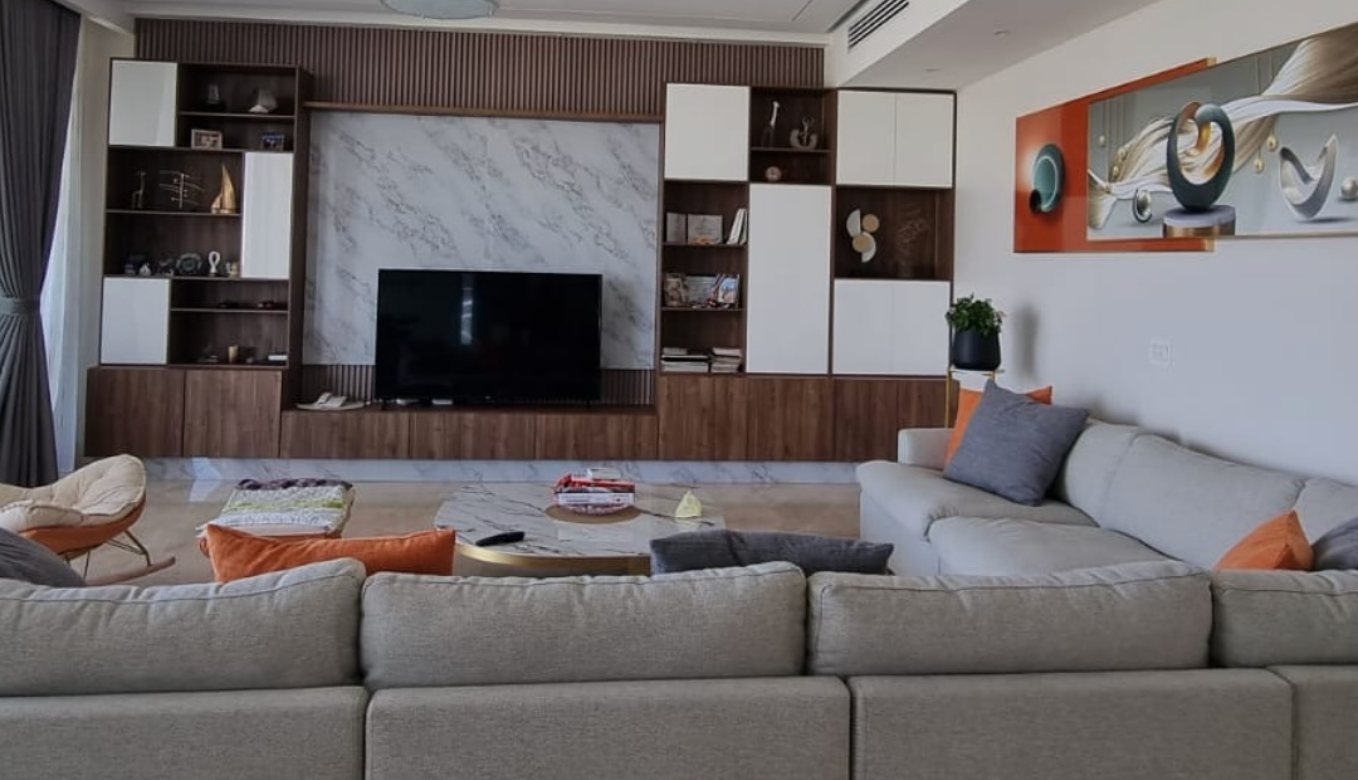 Sala con mueble de pared en madera oscura y blanco, panel tipo mármol para el televisor y sofá gris