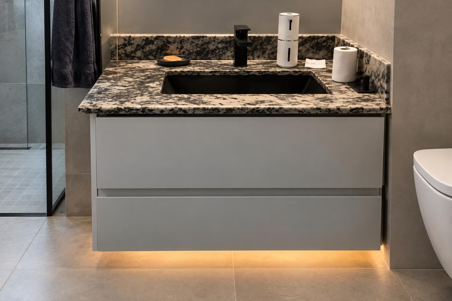 Mueble de baño suspendido gris con cubierta de piedra veteada oscura y lavabo negro
