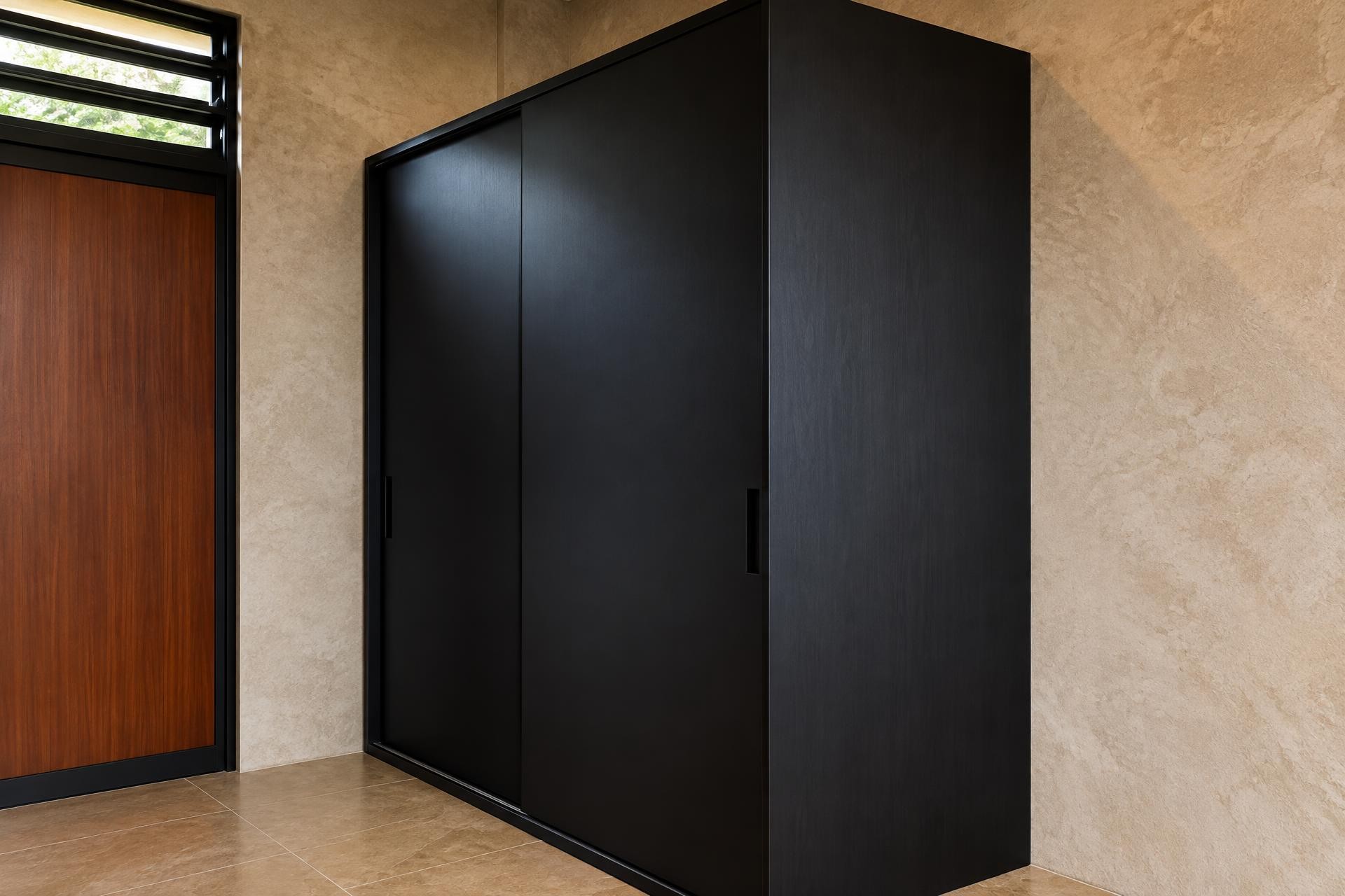 Mueble alto a medida de acabado negro junto a una pared con textura, sin personas