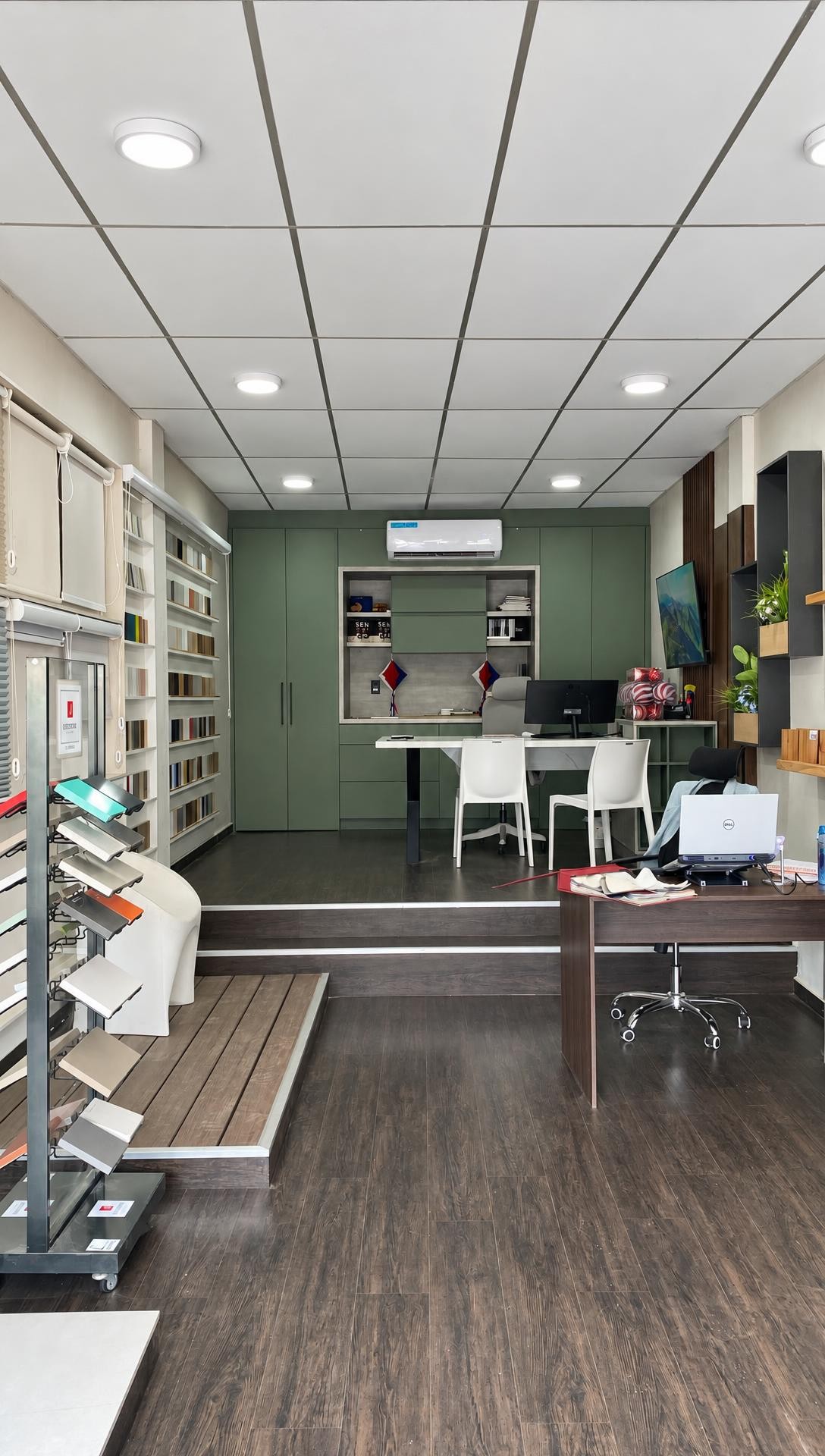 Interior del showroom: oficina con mobiliario verde a medida, exhibidores de muestras y piso de madera